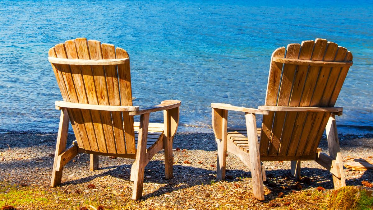 Two Adirondack chairs in front of a lake