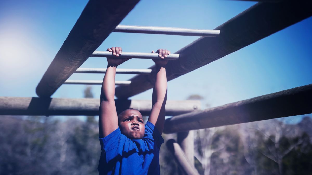 kid toughing it out on monkey bars