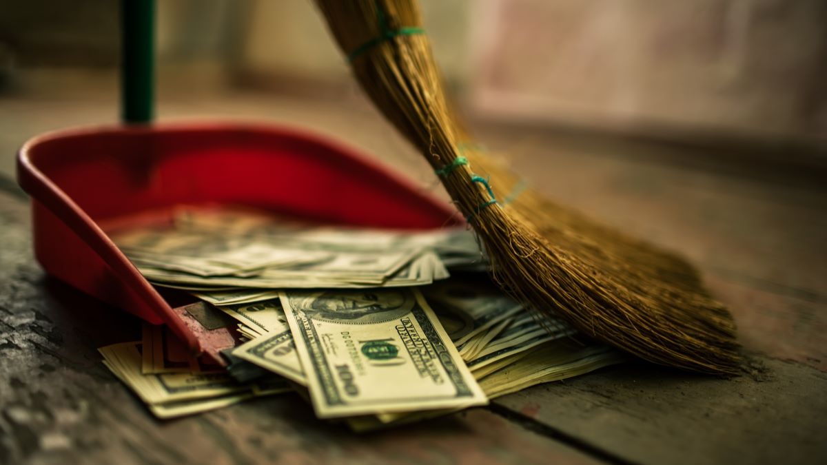 broom sweeping cash into dust pail