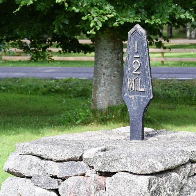 A milestone marker within a green patch of grass signals progress towards goals