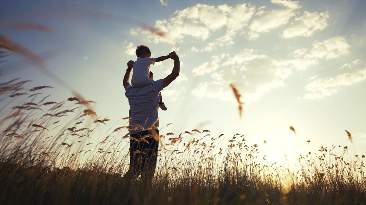 man looking forward with child on his shoulders